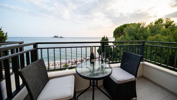 Un balcone con due sedie, un tavolo e una bottiglia di champagne.