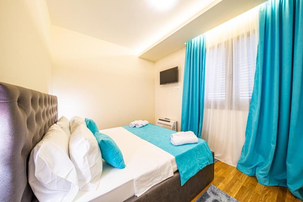 Ein Hotelzimmer mit Bett, Flachbildfernseher und einem Fenster mit Vorhängen.