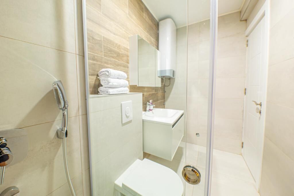 Un bagno moderno con cabina doccia in vetro, lavandino bianco e water.
