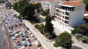 Una zona costiera con una fila di ombrelloni da spiaggia e un edificio con diversi piani e balconi.