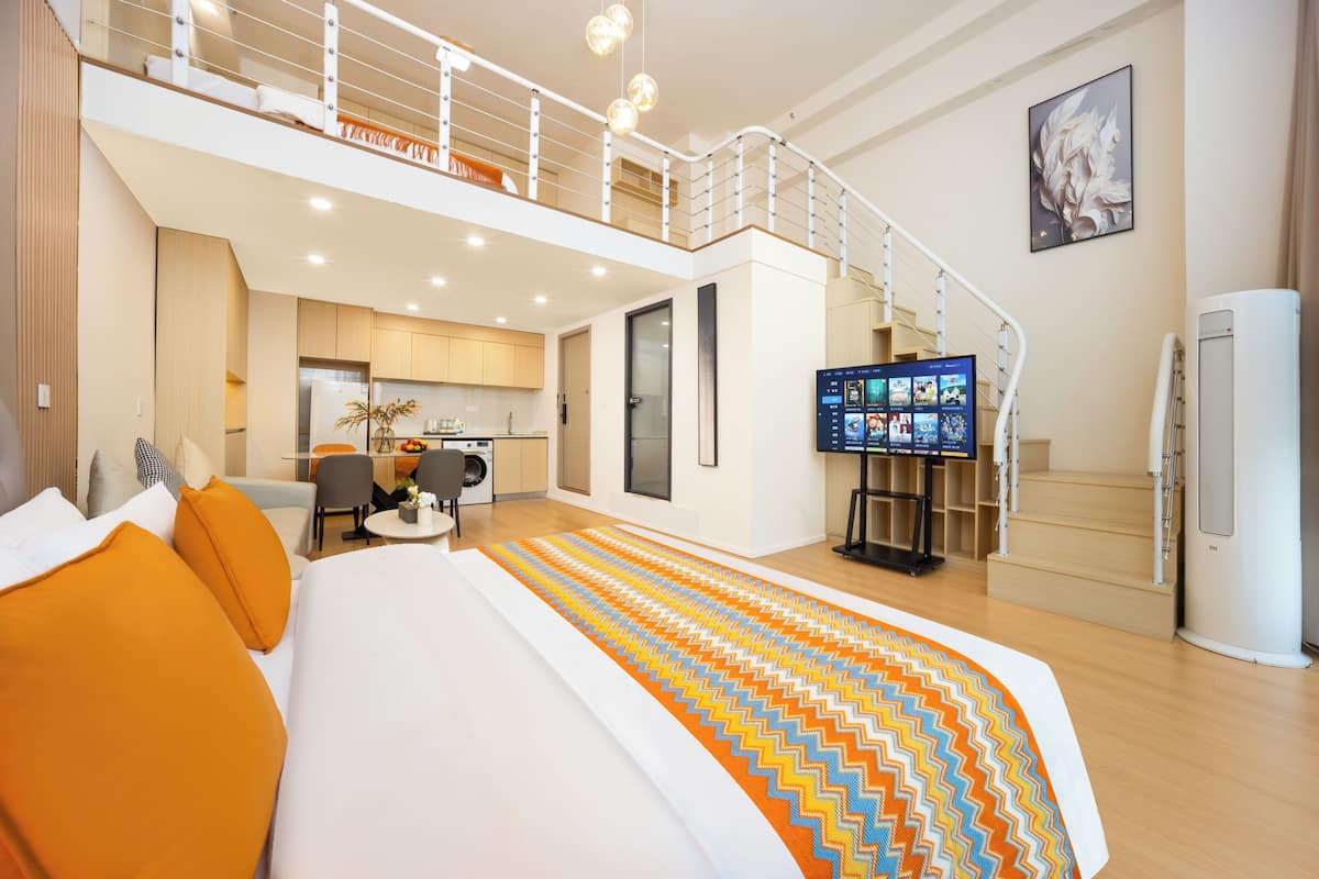 Une chambre d’hôtel avec un grand lit, une télévision, un escalier et un coin cuisine.