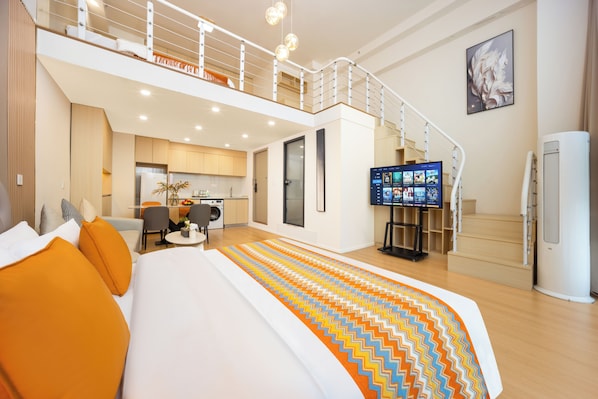 A hotel room with a large bed, a TV, a staircase, and a kitchen area. - The HEJINN House - Design Lofts & Suites (Chengdu)