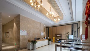 A hotel reception area with a marble reception desk, a chandelier, a digital screen, and a seating area with a glass partition. - The HEJINN House - Design Lofts & Suites (Chengdu)