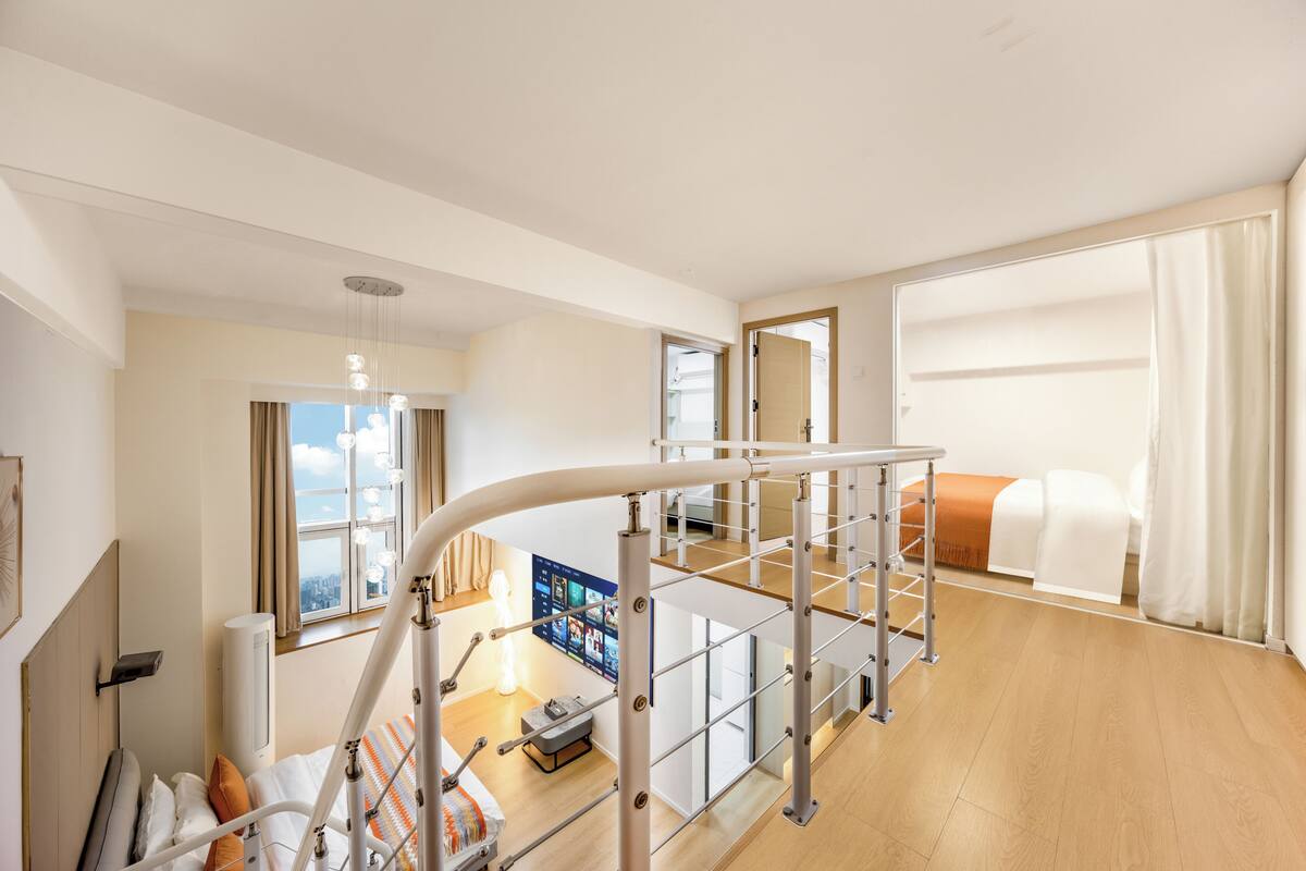 Une chambre d’hôtel moderne avec balcon, un lit, un bureau et une vue sur la ville.