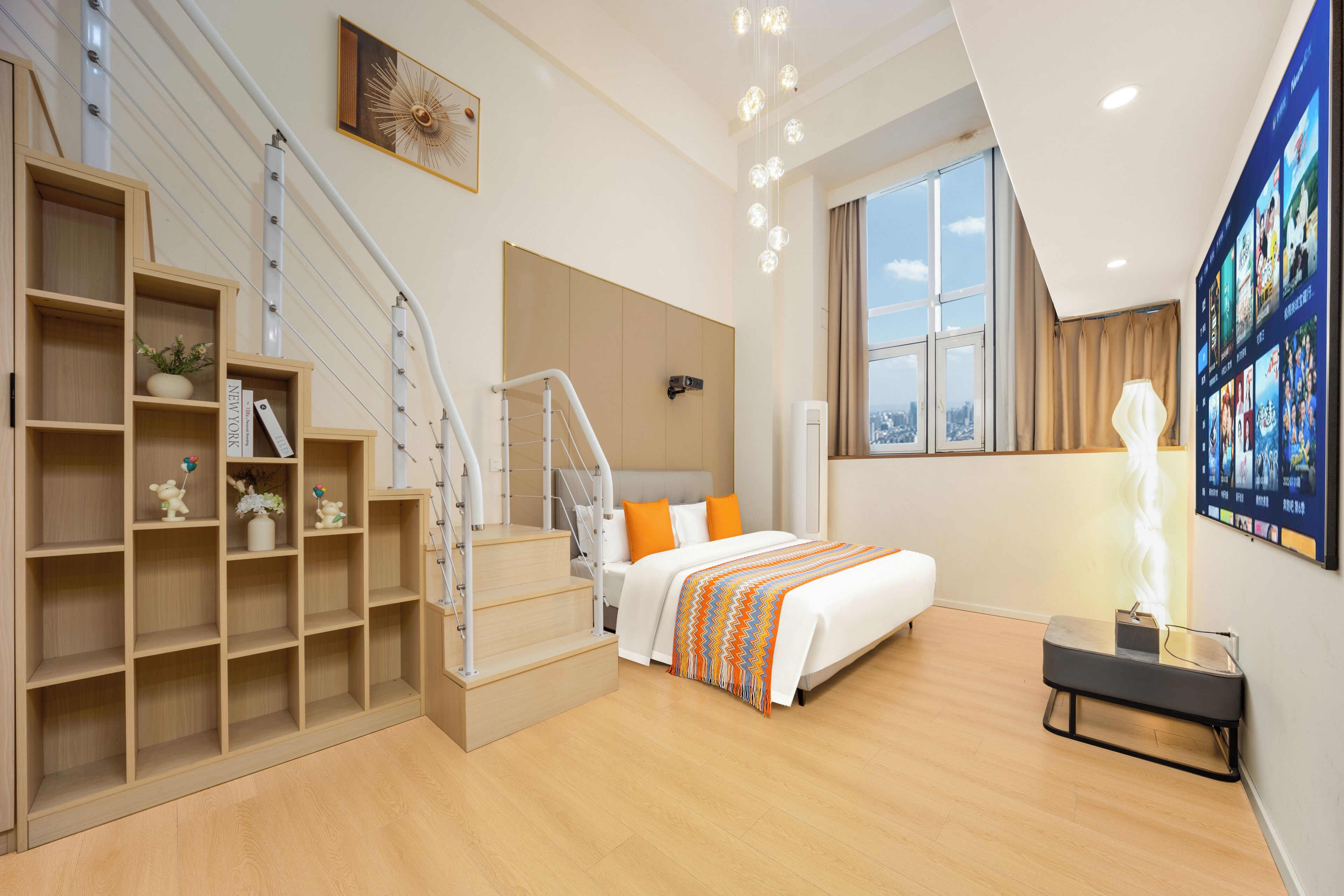 A modern hotel room with a staircase, a bed with a patterned blanket, a large window, and a wall-mounted TV.