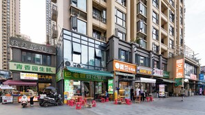 A street with various storefronts, including a restaurant with outdoor seating and a sign for a noodle shop. - The HEJINN House - Design Lofts & Suites (Chengdu)