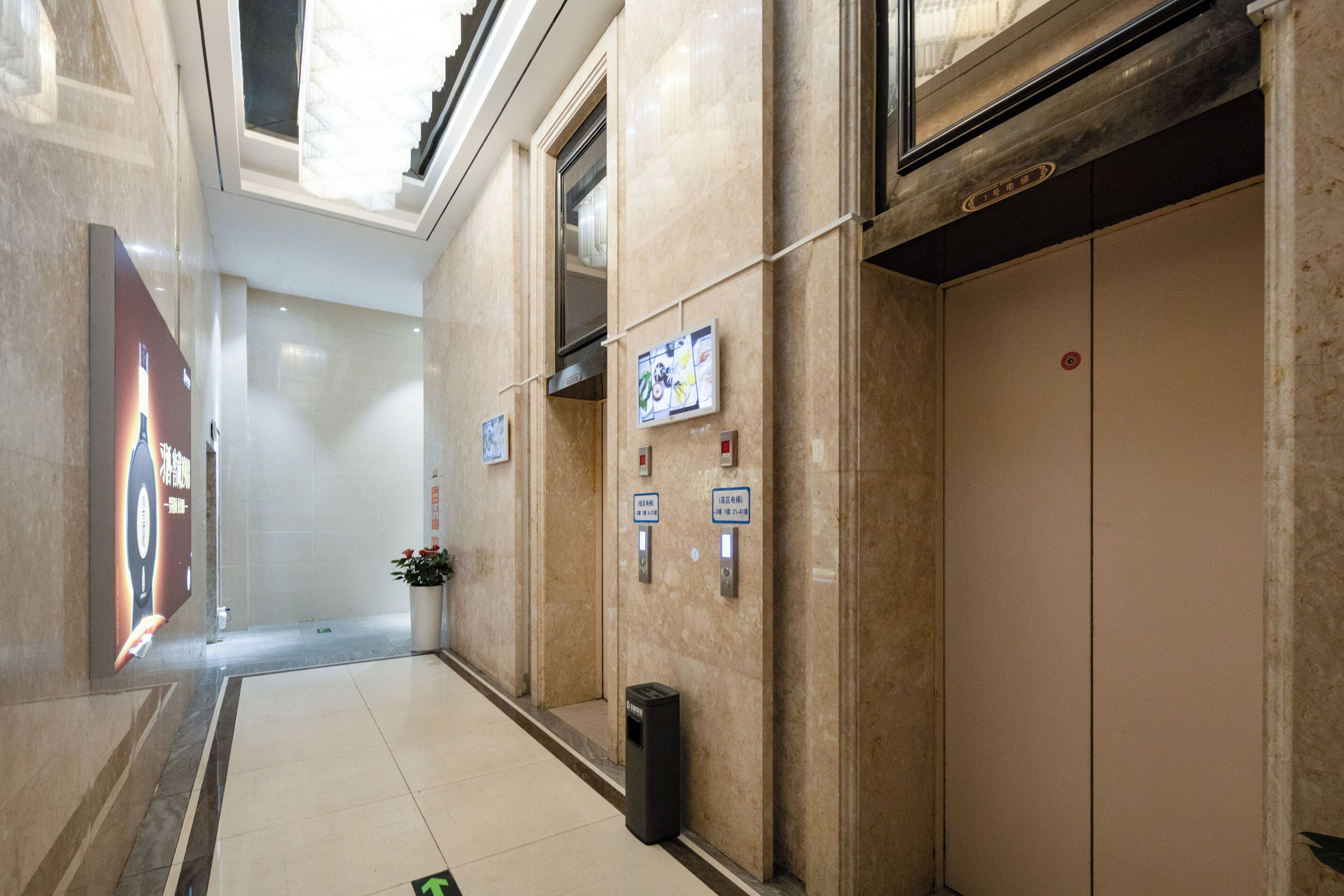 A hallway with a tiled floor, a trash bin, and a wall with emergency contact signs.