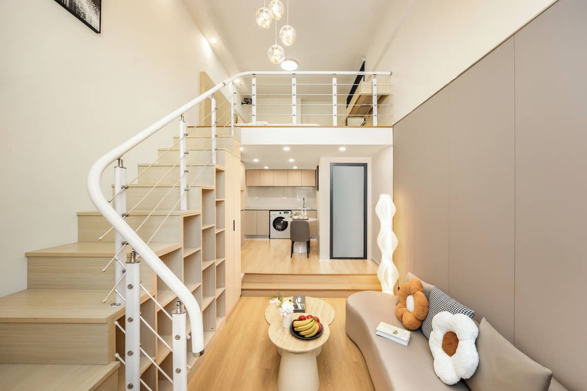 Un intérieur moderne comprenant un escalier, un coin repas et un canapé agrémenté de coussins décoratifs.