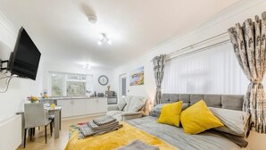 A bedroom with a bed, a desk, a chair, a television, and a window with curtains. - Apartment Sleeps 2 With Parking and Pets Welcome (Narberth)
