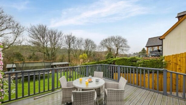 A deck with a round table and chairs, surrounded by a wooden fence, overlooking a grassy area with trees. - Apartment Sleeps 2 With Parking and Pets Welcome (Narberth)