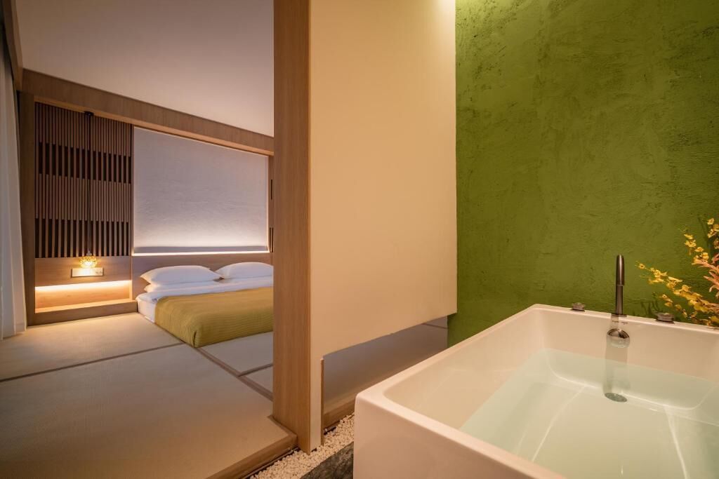 Un baño moderno con bañera, cabecera de madera y pared verde.