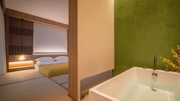 Un baño moderno con bañera, cabecera de madera y pared verde.