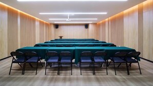 Ein Konferenzraum mit einem langen Tisch, Stühlen und einem Rednerpult.