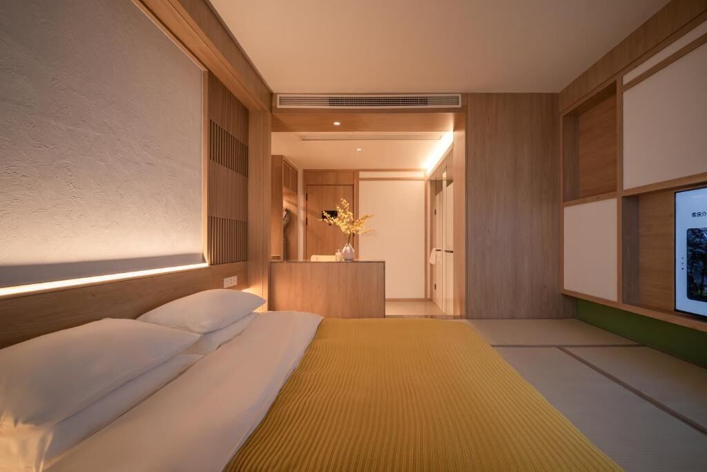 Een moderne hotelkamer met een bed, nachtkastje en een televisie.