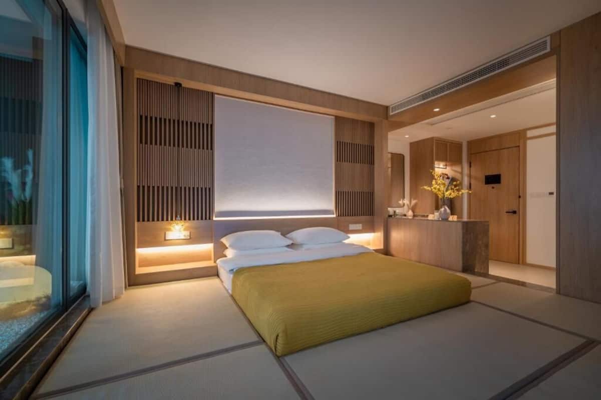 Una habitación de hotel moderna con una cama grande, una mesita de noche, un espejo y una ventana.