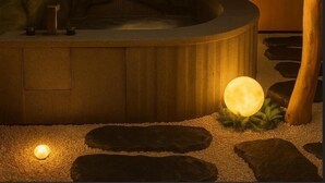 Ein Wellnessbereich mit Whirlpool, einer Holztür und einem Steinweg.