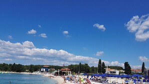 Una spiaggia con un bar, cieli sereni e un litorale ciottolato.