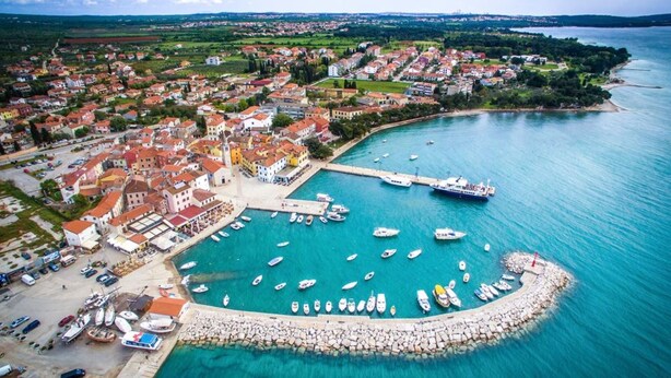 Vista aerea di una cittadina costiera con un porto turistico, case e barche.