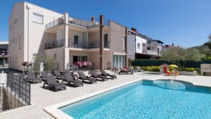 Un hotel con piscina, poltrona a sdraio e balconi.