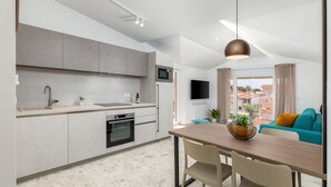 Una cucina moderna con zona pranzo, una TV a schermo piatto e vista sugli edifici.