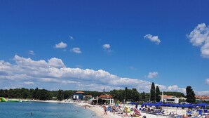 A beach with a bar, clear skies, and a pebbled shore. - Villa Nina - apartment Sea view 30 by Villas Guide (Fažana)