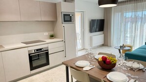 A modern kitchen with a microwave, oven, and dining area set for a meal. - Villa Nina - apartment Sea view 30 by Villas Guide (Fažana)