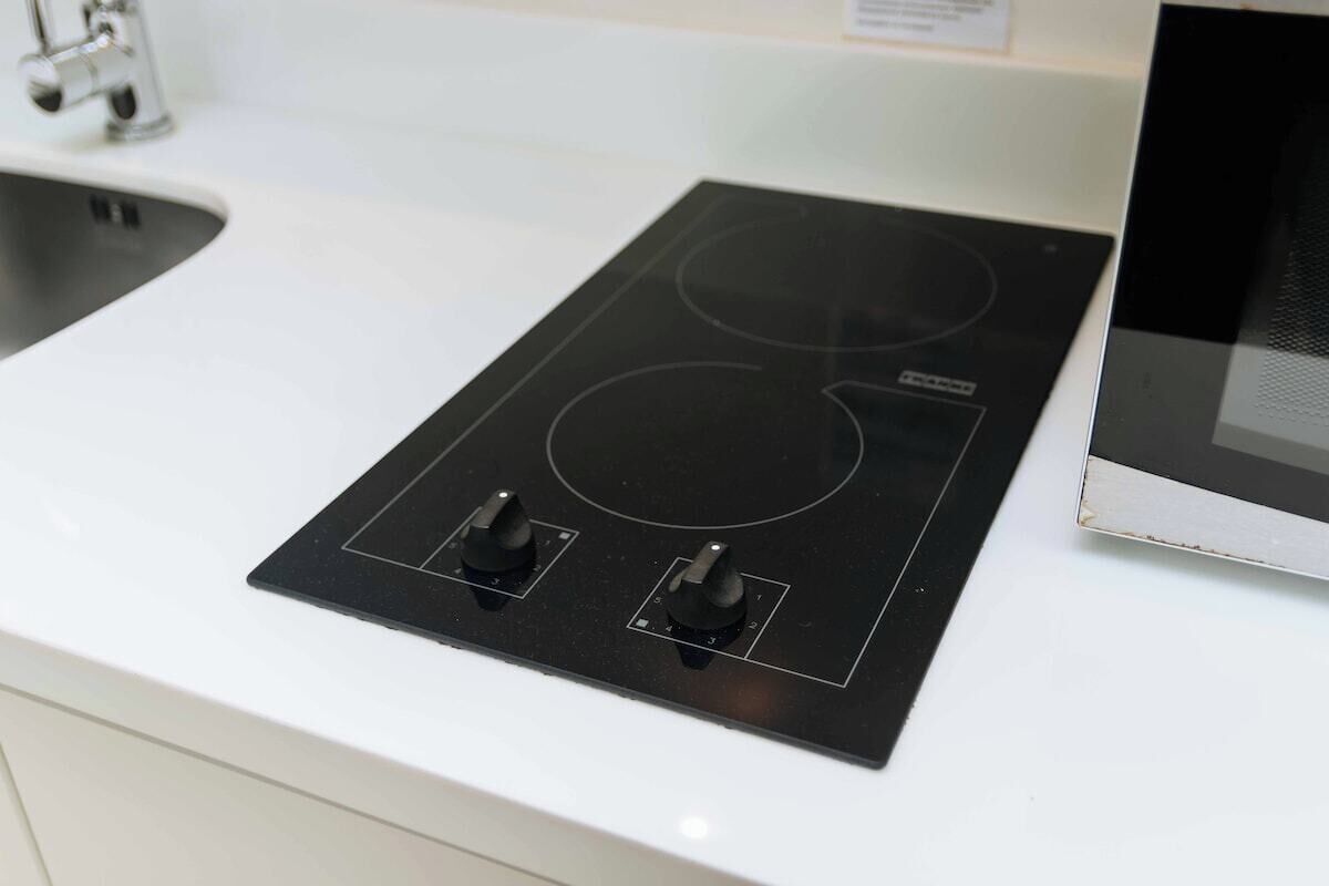 A kitchen with a black induction cooktop and a microwave.