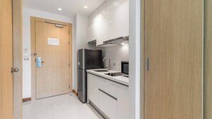 A compact kitchen with a refrigerator, microwave, and sink. - Beachfront Stay Walk to Beach • Gym • Pool C273 (Rawai)