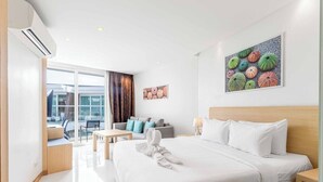 A modern hotel room with a large bed, a desk, a sofa, and a balcony with a view. - Beachfront Stay Walk to Beach • Gym • Pool C273 (Rawai)