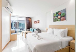 A modern hotel room with a large bed, a desk, a sofa, and a balcony with a view. - Beachfront Stay Walk to Beach • Gym • Pool C273 (Rawai)