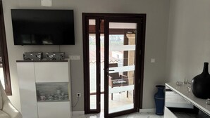 A room with a TV, a cabinet with kitchenware, a blue vase, and a marble floor. - Tourist House in Boa practically brand new and with beautiful sea views. (Noia)