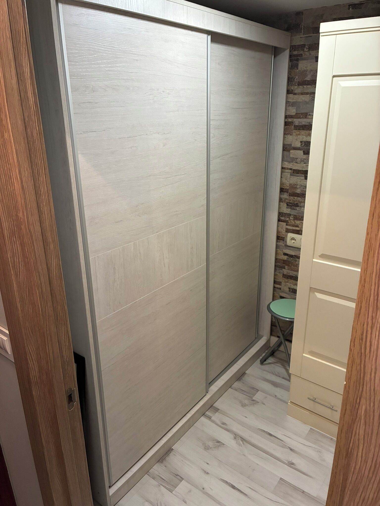 A room with a sliding door, a small green table, and a wardrobe.