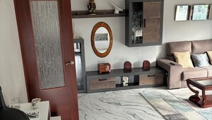 A modern living room with a marble floor, a sofa, a coffee table, a TV, and a decorative mirror. - Tourist House in Boa practically brand new and with beautiful sea views. (Noia)