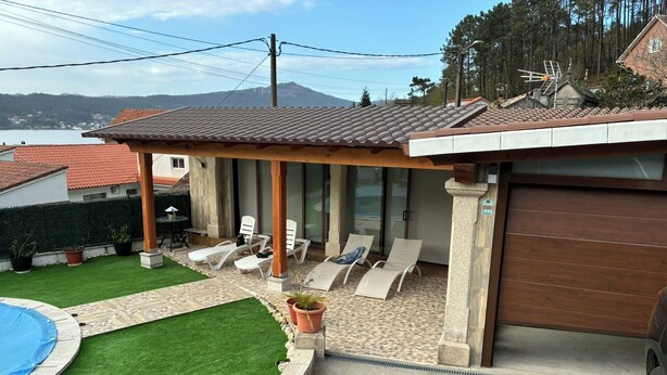 A covered outdoor seating area with lounge chairs, a swimming pool, and a view of a mountain. - Tourist House in Boa practically brand new and with beautiful sea views. (Noia)