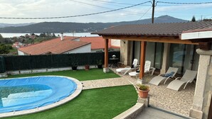 A backyard with a swimming pool, artificial grass, and lounge chairs. - Tourist House in Boa practically brand new and with beautiful sea views. (Noia)