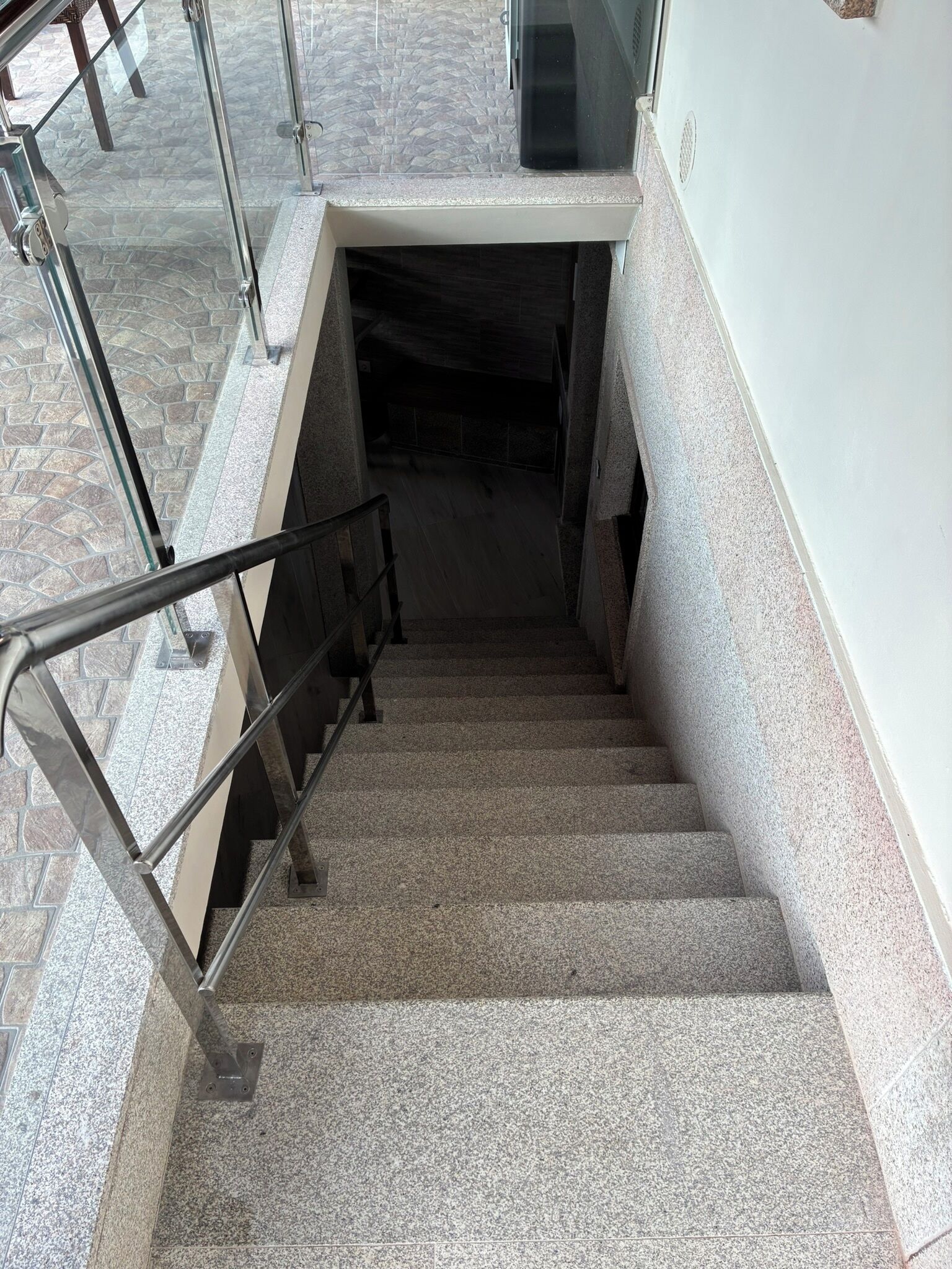 A staircase with metal railings, granite steps, and a glass door at the top.