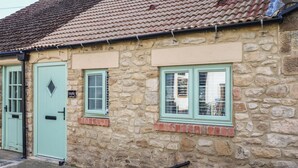 A stone building with a green door and windows, a small brick ledge, and a metal gutter. - 2 Low Road (Bishop Auckland)