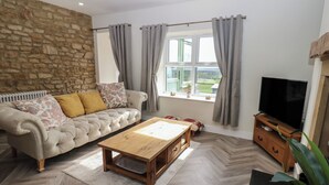 A living room with a sofa, a coffee table, a TV, and a view of the outdoors. - 2 Low Road (Bishop Auckland)