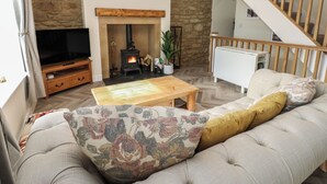 A living room with a stone wall, a fireplace, a sofa, a coffee table, and a TV. - 2 Low Road (Bishop Auckland)