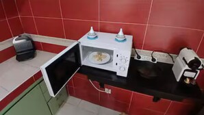 Cuina amb rajoles vermelles, microones, torradora i petit electrodomèstic al taulell.