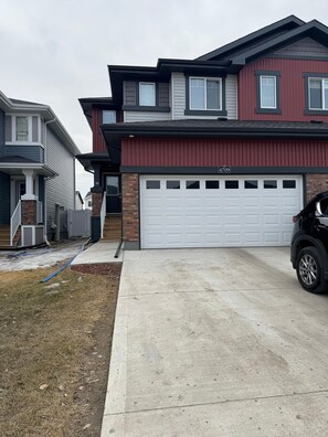 Une maison d’habitation à deux étages, dotée d’un garage, d’une allée et d’une pelouse.