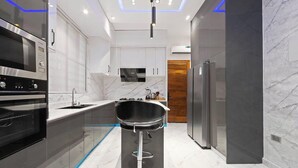 Una cocina moderna con horno empotrado, microondas, pileta y un taburete de bar.