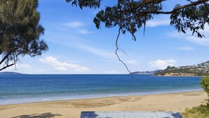 Ein Strand mit einer Holzterrasse, blauem Himmel und ruhiger See.