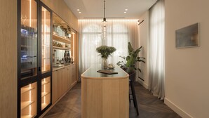 A modern kitchen with wooden cabinetry, a central island, and a hanging light fixture. - The Castelletto (Montebelluna)