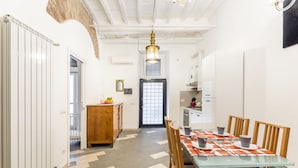 A modern kitchen with white cabinets, a wooden dining table, and a patterned floor. - Navona Harmony Apartment - Spagnoli (Rome)