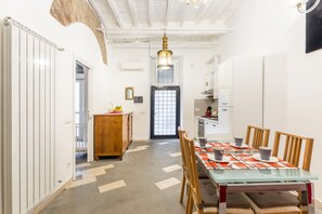A modern kitchen with white cabinets, a wooden dining table, and a patterned floor. - Navona Harmony Apartment - Spagnoli (Rome)