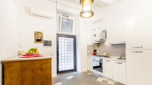 A modern kitchen with white cabinets, a wooden countertop, a built-in oven, and a window with a grid pattern. - Navona Harmony Apartment - Spagnoli (Rome)