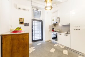A modern kitchen with white cabinets, a wooden countertop, a built-in oven, and a window with a grid pattern. - Navona Harmony Apartment - Spagnoli (Rome)
