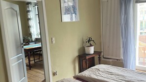 Un dormitorio con dos camas, televisión, aire acondicionado, un cuadro enmarcado y una ventana con cortinas.