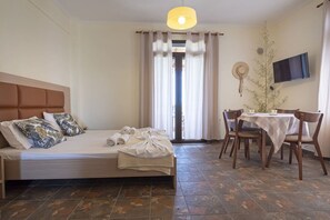 Een slaapkamer met een bed, nachtkastje, stoel, eettafel en televisie.
